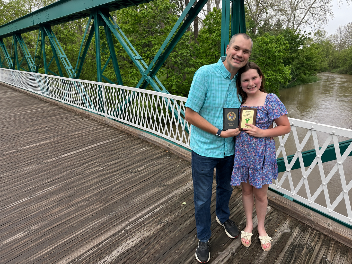 Thomas Spry with his daughter and her Yorktown Elementary honor roll plaque on the White River bridge
